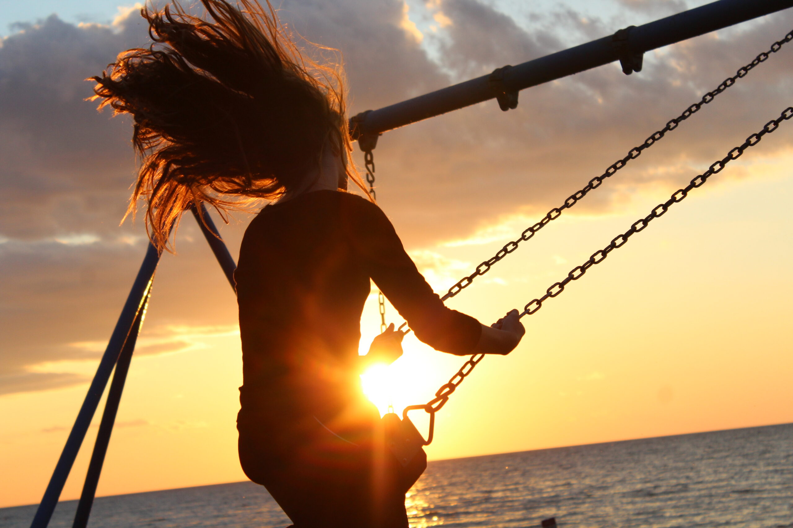 female on swing by water