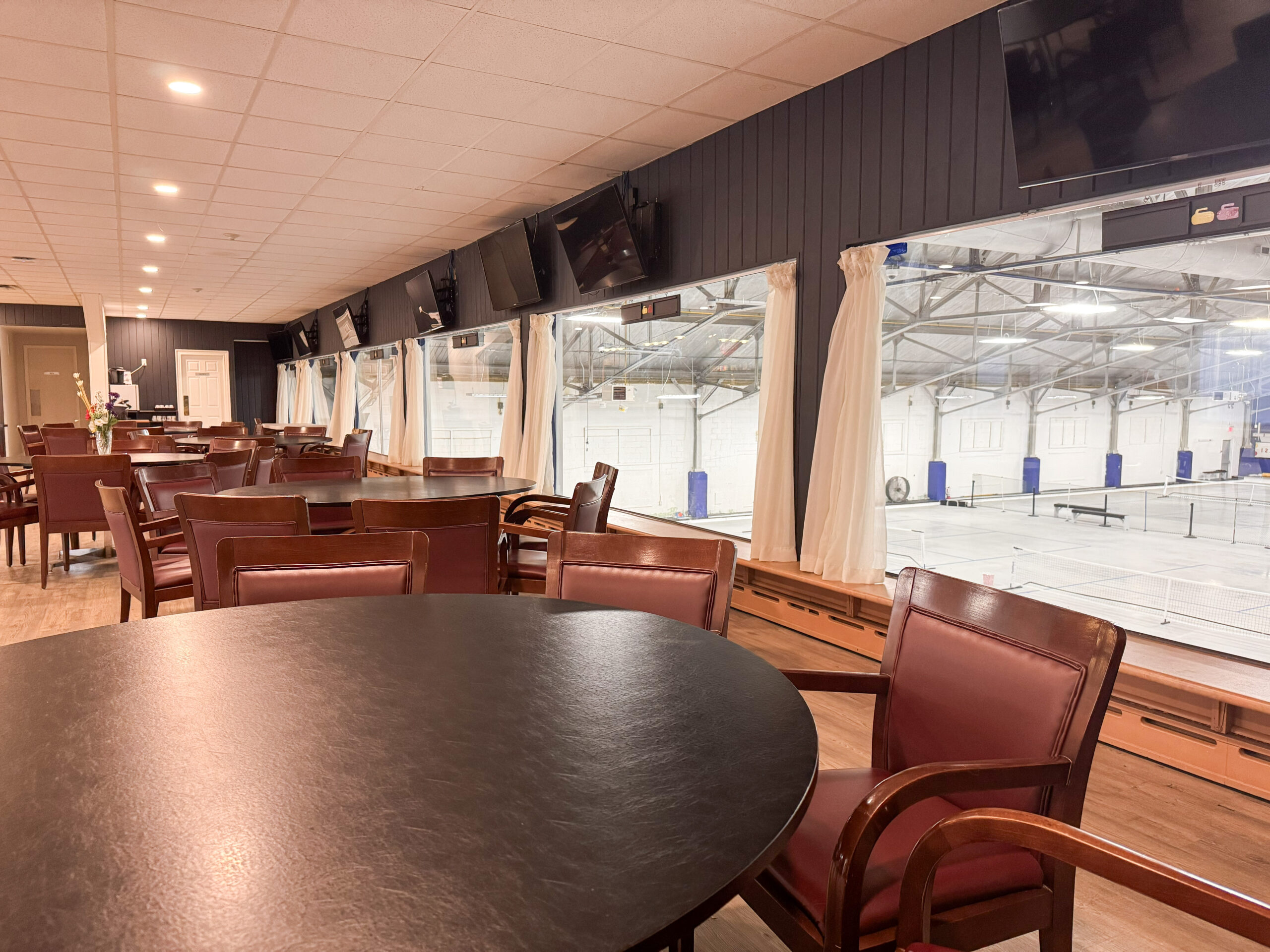 Interior of Barrie Curling Club wedding venue showing reception tables and chairs with the ice rink visible through the windows