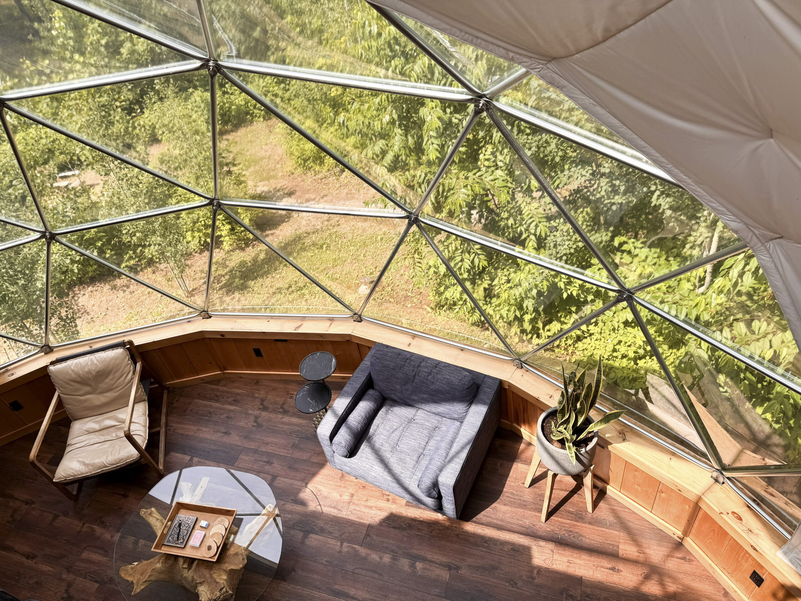 Interior of overnight geodesic dome rental at Glen Oro Farm with lounge seating and forest views, Ontario wedding venue