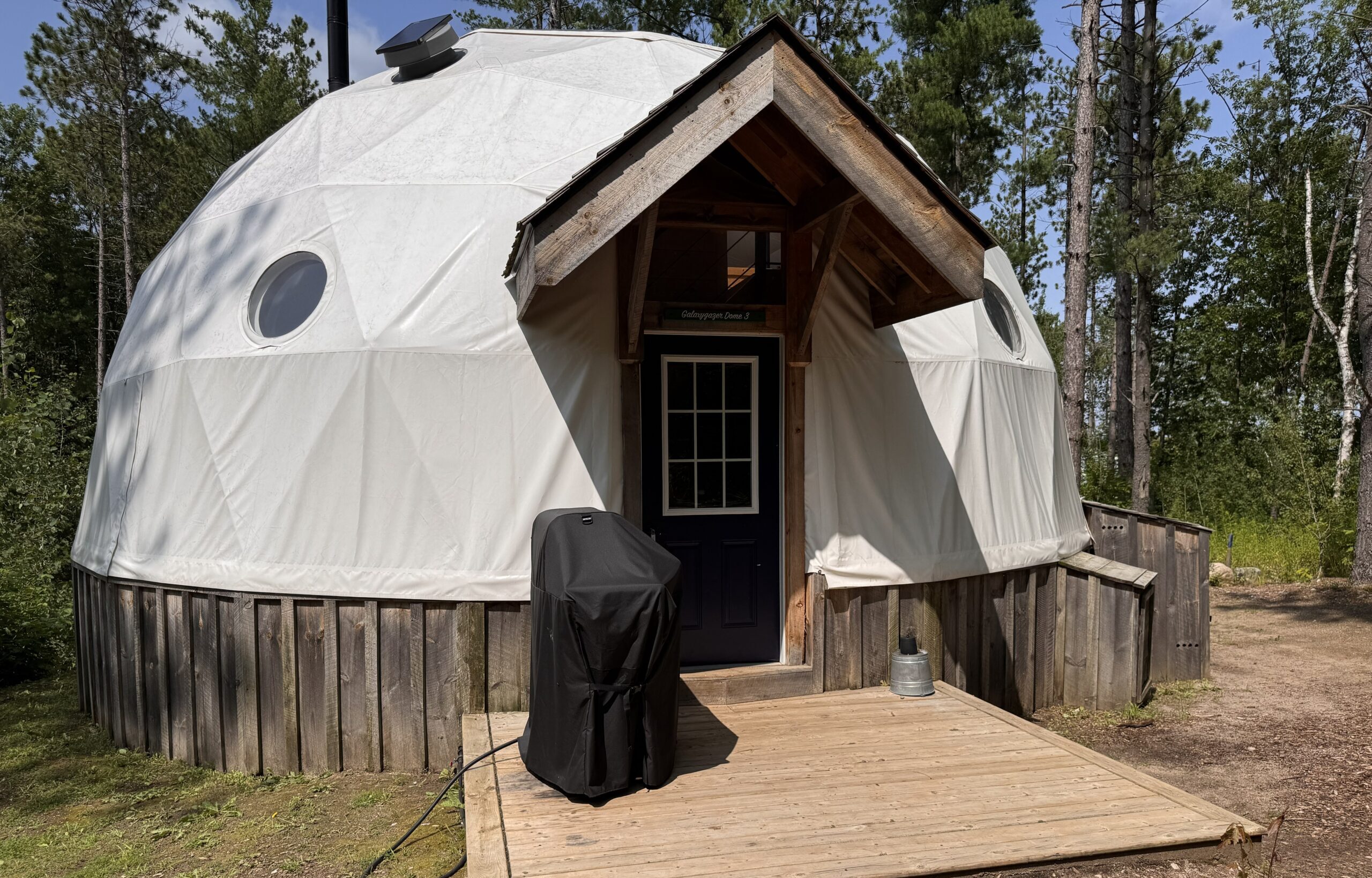 Geodesic glamping dome with wood entrance and deck at Glen Oro Farm, Oro-Medonte, Ontario