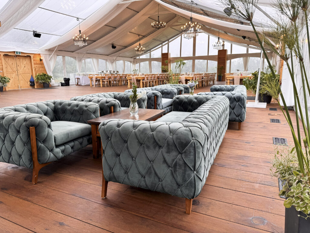 Chesterfield-style lounge seating and chandeliers inside the reception tent at Glen Oro Farm