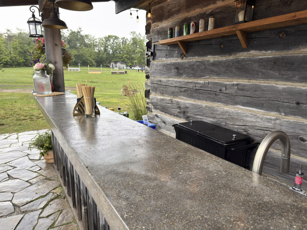 Outdoor bar counter at the Ranger Cabin, with reclaimed wood siding and views over the equestrian paddocks
