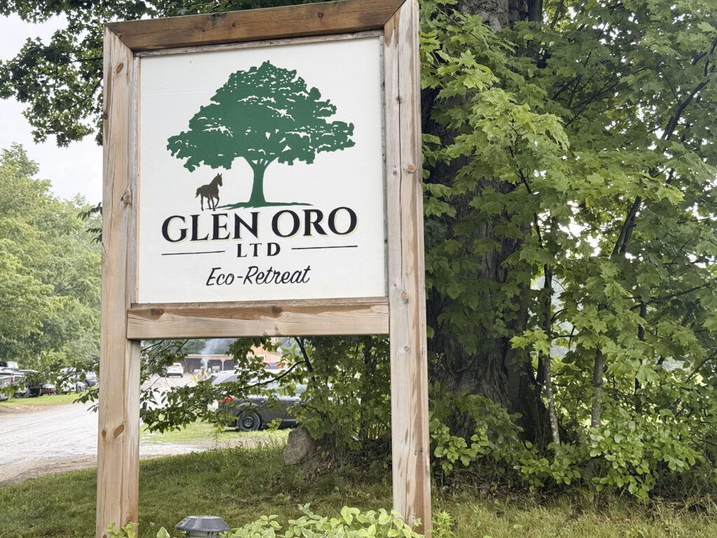 Wooden entrance sign for Glen Oro Farm at the property's driveway