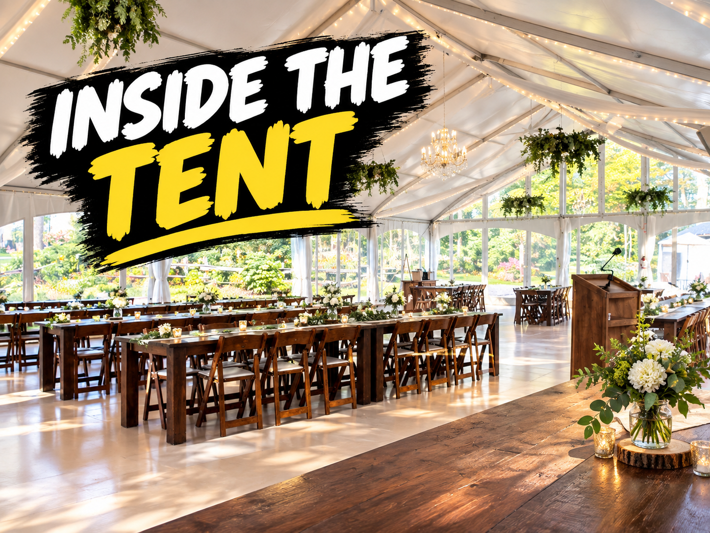 Inside the wedding tent at Northbrook Farm: long farm tables, hanging greenery and wood floors under a white tent with large windows