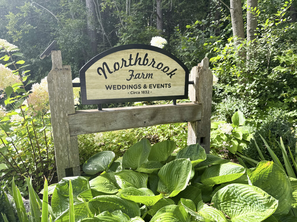 Northbrook Farm Weddings & Events wooden sign surrounded by lush hostas