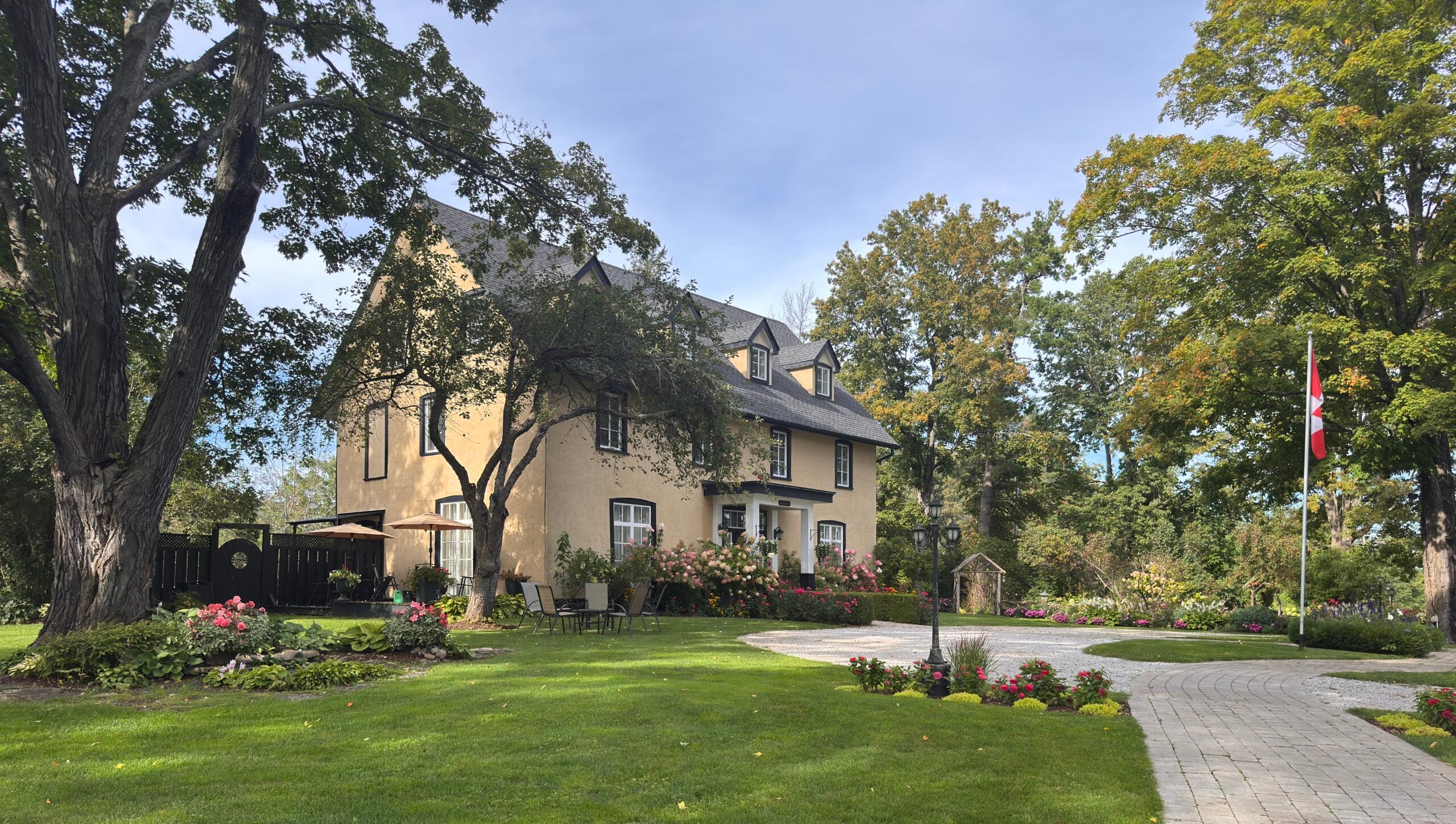 Historic stucco farmhouse surrounded by mature trees, gardens, and a manicured lawn at Northbrook Farm wedding venue near Orillia, Ontario