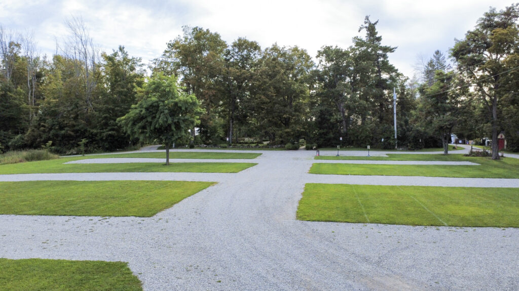 Gravel parking area lined with grass and mature trees at Northbrook Farm